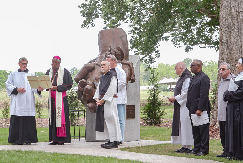 Charleston Bishop Jacques Fabre-Jeune (second from left) leads the blessing of the sculpture "Thy Father's Hand," by artist Garland Weeks, on April 26, 2025, in the new Meditation Garden of Truth and Reconciliation at Mepkin Abbey in Moncks Corner, South Carolina. (NCR screenshot/YouTube/Mepkin Abbey)