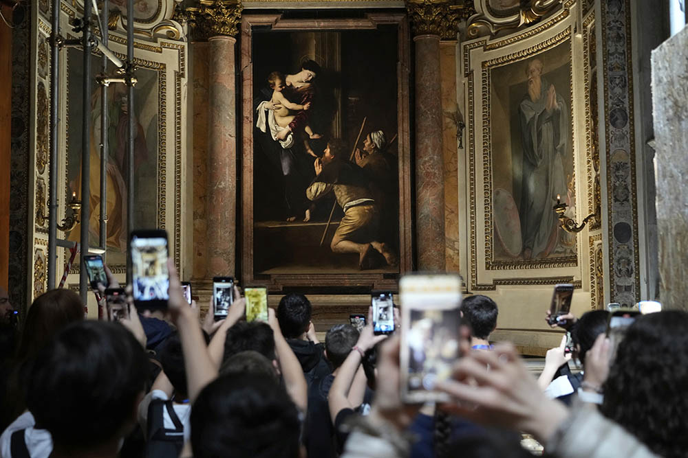 Tourists admire the Pilgrims' Madonna, of Caravaggio is seen at the Basilica of St. Augustine in Rome on May 22, 2025. (AP Photo/Gregorio Borgia)