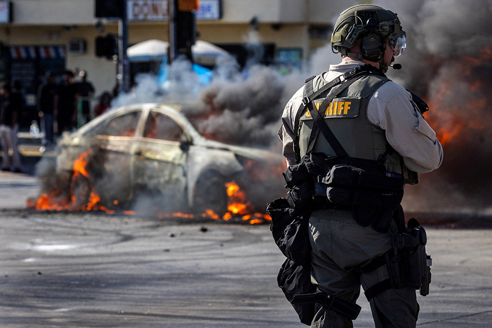 Smoke rises from a burning car on Atlantic Boulevard during a standoff by protesters and law enforcement, following multiple detentions by U.S. Immigration and Customs Enforcement in Compton, Calif., June 7, 2025. (OSV News/Reuters/Barbara Davidson) Smoke rises from a burning car on Atlantic Boulevard during a standoff by protesters and law enforcement, following multiple detentions by U.S. Immigration and Customs Enforcement in Compton, Calif., June 7, 2025. (OSV News/Reuters/Barbara Davidson)
