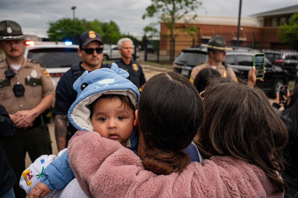 A mother holds her child as multiple immigrant rights groups gather at the Department of Homeland Security field office in Nashville, Tenn., to protest what they believe to be a multi-agency operation to detain noncitizens overnight in Nashville, May 4, 2025. (OSV News/Reuters/Seth Herald)