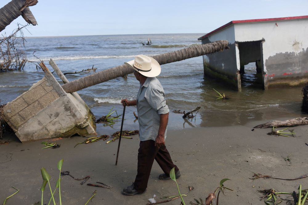 A man walks remains of house near water in El Bosque, Mexico. 