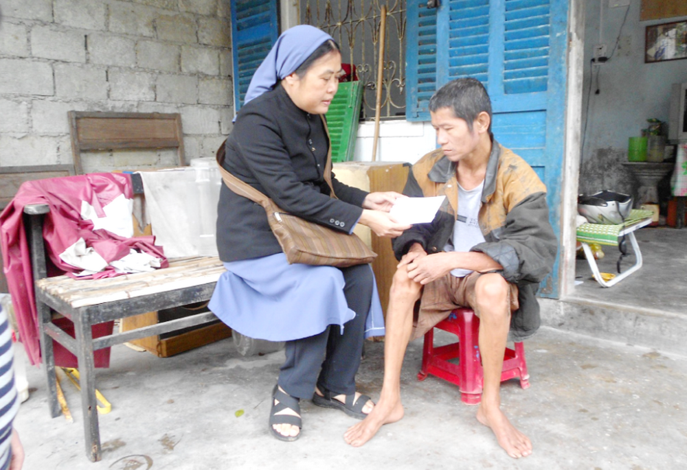 Sr. Mary Pham Thi Phu offers gifts to a man in Phu Loc District in Thua Thien Hue