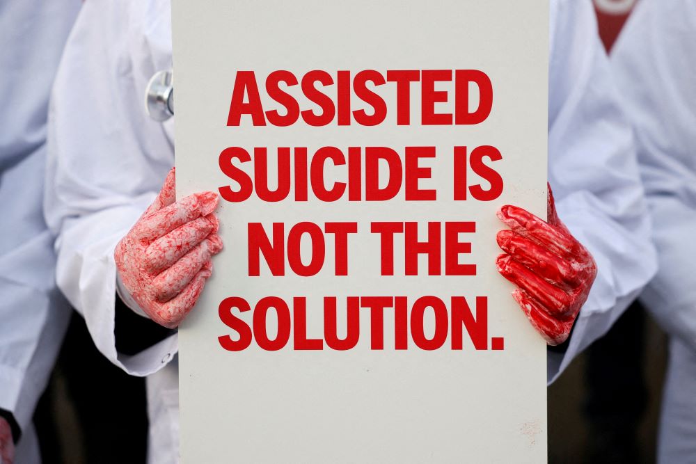 A protester holds a sign that reads "Assisted suicide is not the answer" card outside the Parliament in London. 