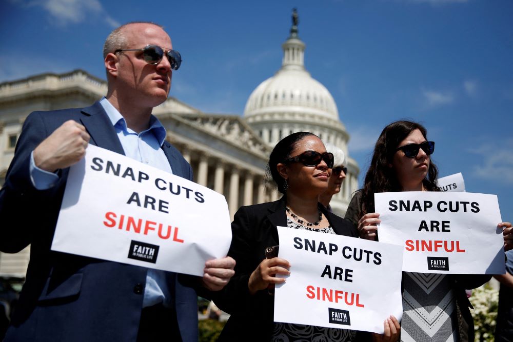  People hold up signs protesting against cuts to the Supplemental Nutrition Assistance Program.