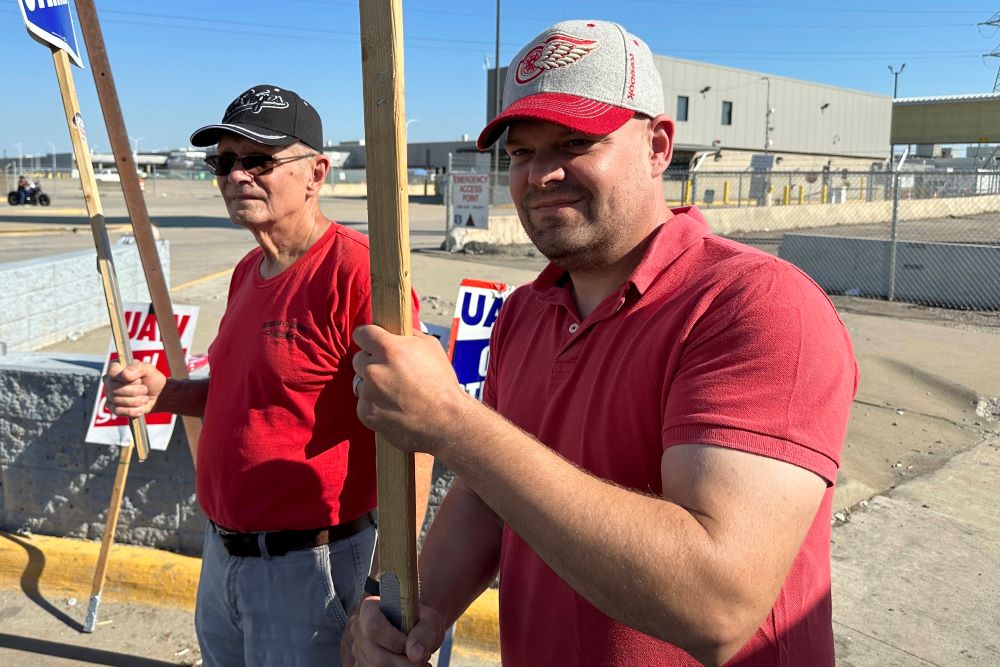 Striking United Auto Workers member Chris Jedrzejek, right, and his father picket outside Ford Motor Co.'s Michigan Assembly Plant Oct. 2, 2023, in Wayne, Mich.