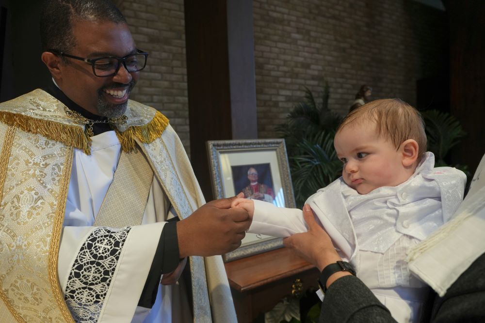 Ricky Malebranche, who was ordained as a priest June 7, holds the hand of 9-month-old Andres Roman Marquez after baptizing him at St. Louis Catholic Church in Alexandria, Va., May 24. (AP/Luis Andres Henao) Ricky Malebranche, who was ordained as a priest June 7, holds the hand of 9-month-old Andres Roman Marquez after baptizing him at St. Louis Catholic Church in Alexandria, Va., May 24. (AP/Luis Andres Henao)
