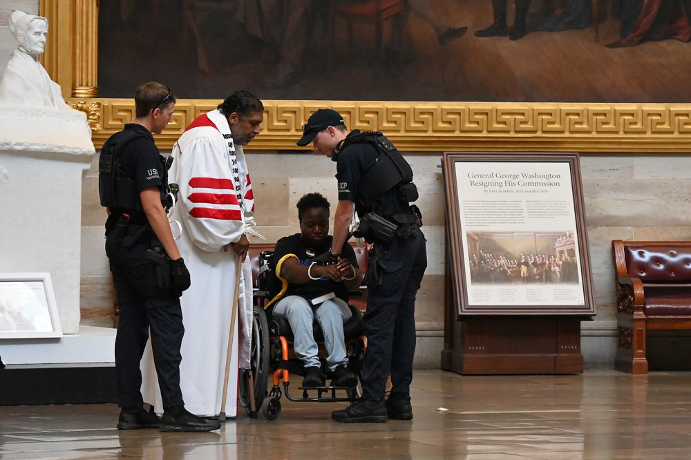 Police arrest the Rev. William Barber II, center left, and Suvya Carroll, center right, in the U.S. Capitol Rotunda June 2 in Washington. Nine people arrested were charged with "crowding, obstructing and incommoding." (RNS photo/Jack Jenkins)