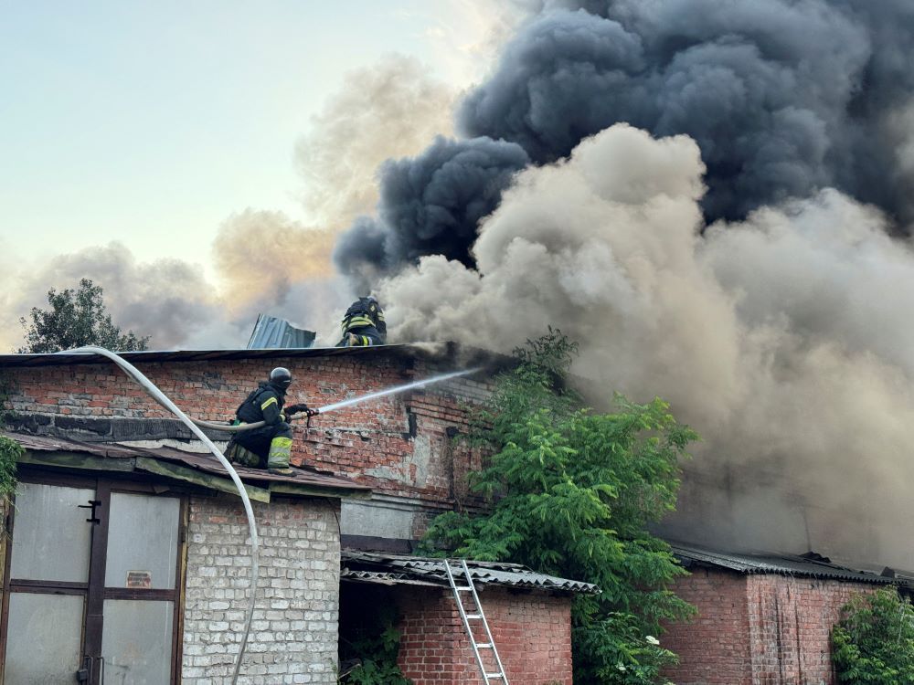 Firefighters work amid smoke from drone attack.