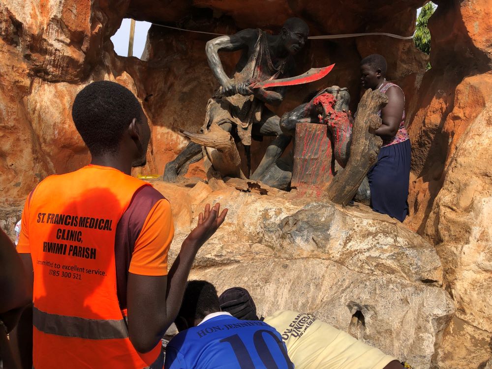 A pilgrim prays in front of a sculpture depicting the execution of a Uganda martyr.