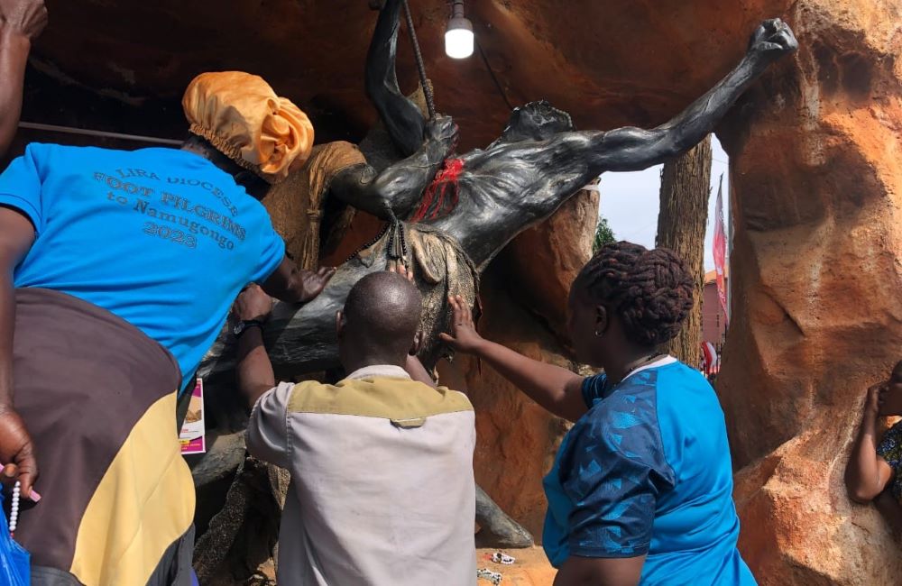 Pilgrims pray in front of a sculpture depicting the brutal execution of a Uganda martyr. 