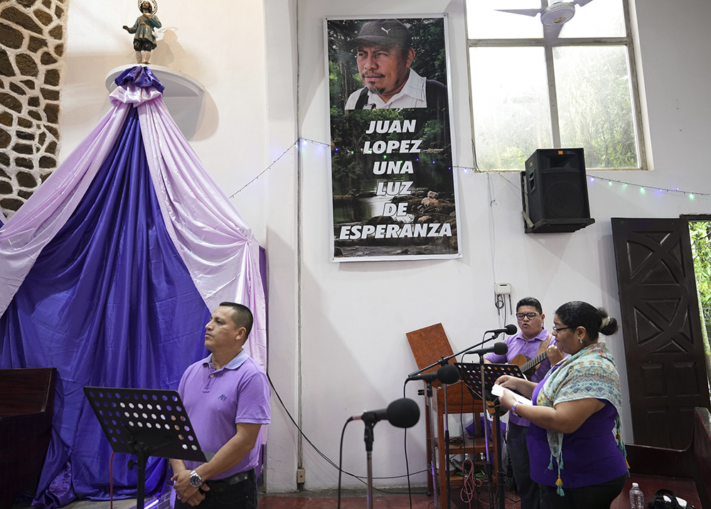 A poster of slain environmentalist Juan López hangs on a wall at the San Isidro Labrador church during a Mass in Tocoa, Honduras, on Dec. 8, 2024. (AP photo/Moises Castillo)