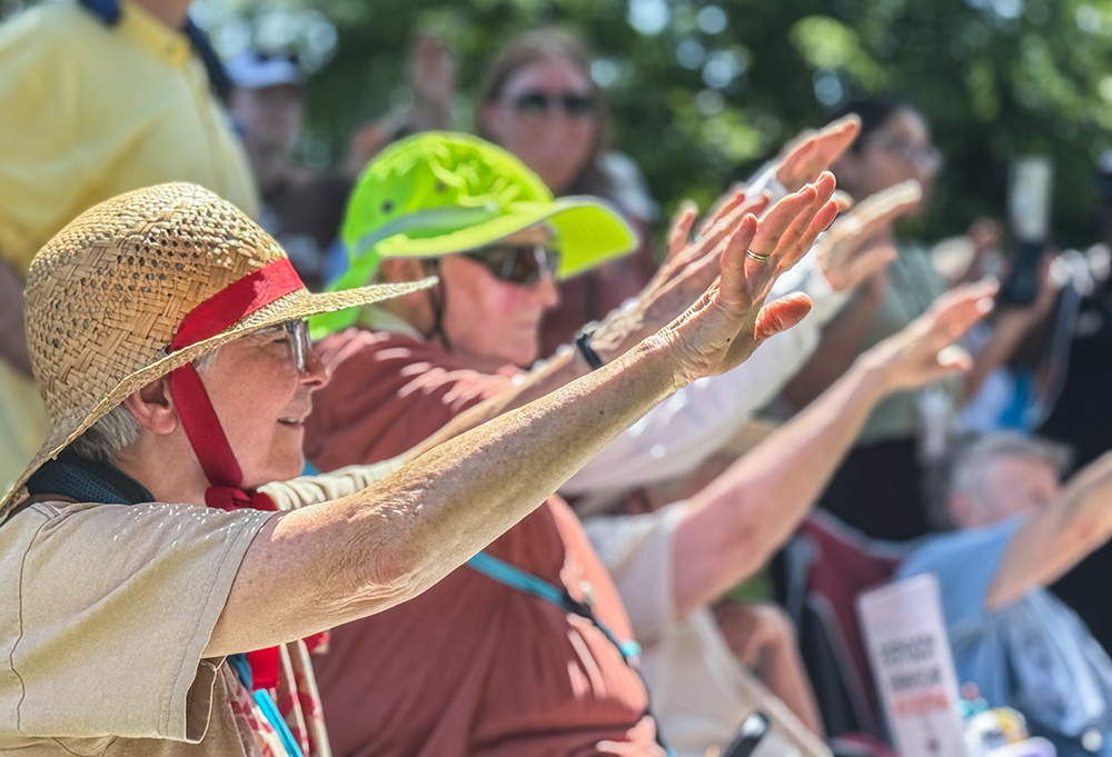 Sisters on the grounds of the U.S. Capitol extend their hands June 25, 2025, as they pray over letters sent to lawmakers opposing a bill that they say will hurt the poor in their communities. A group of about 200 Catholic women religious and their supporters attended the Sisters Speak Out event in Washington, even as temperatures reached almost 100 degrees. (GSR photo/Rhina Guidos)