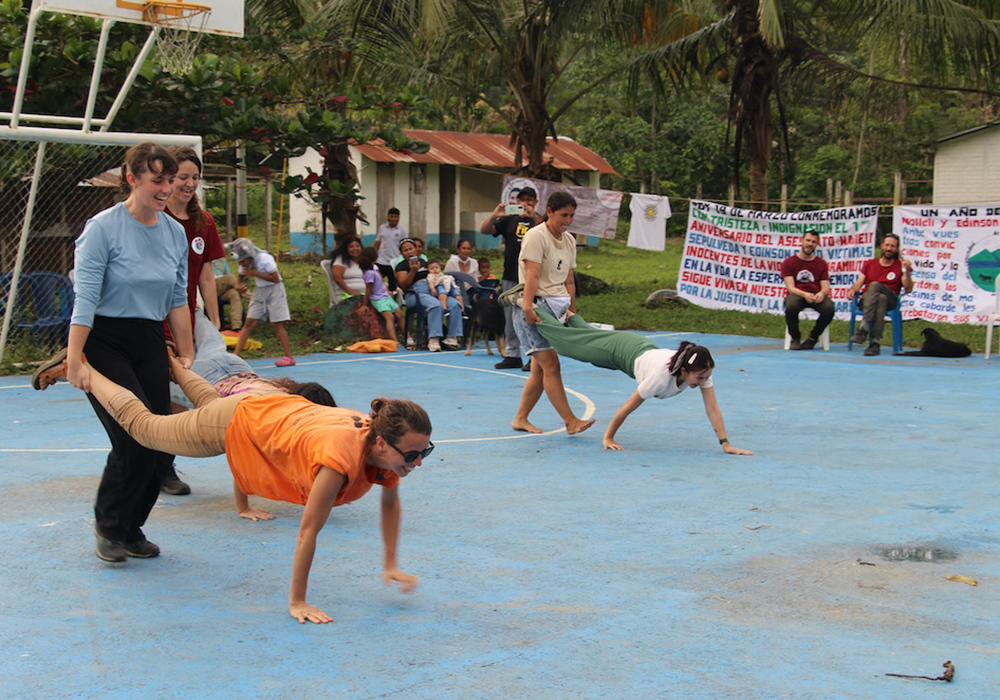 Observadores internacionales compitieron con miembros de la comunidad en una carrera de carretillas en la cancha durante la celebración del aniversario de la comunidad. (Foto: Tracy L. Barnett)