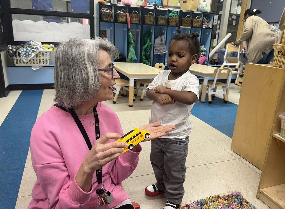 Jennifer Heinemann, Operation Breakthrough's director of stewardship and planned giving, reads to a toddler. The early education building is divided into "neighborhoods" — the purple neighborhood is for babies, green is for toddlers, etc. — and is organized by families so that all siblings fall under "green," for example, so moms interact with consistent staff. (GSR photo/Soli Salgado)