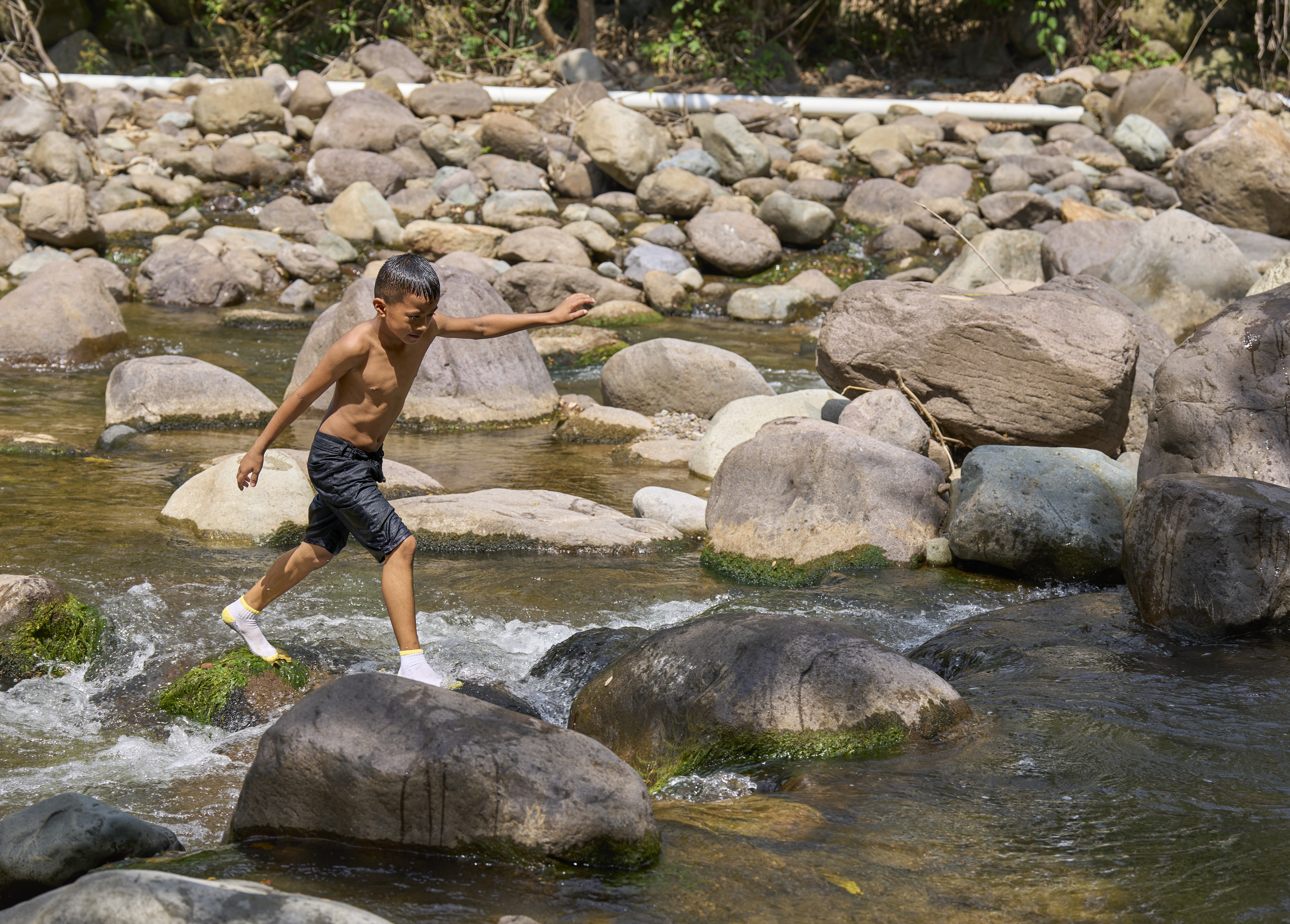 Mikey del Cid, 9, plays in the Guapinol River in northern Honduras. The river and those who live alongside it are threatened by mining operations — currently suspended by the government — in the Carlos Escaleras National Park. Communities resisting the mining operations received support from Juan López, who was assassinated Sept. 14, 2024, in nearby Tocoa. (NCR photo/Paul Jeffrey)