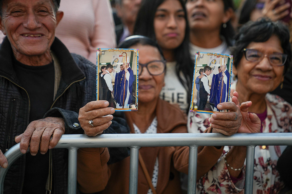 Victoria Herrera, a Chiclayana, holds photos of her grandchildren with Bishop Robert Prevost, during an outdoor Mass in Chiclayo, Peru, on May 10, where thousands prayed for Prevost's success in his new role as Pope Leo XIV. (GSR photo/Manuel Rueda)