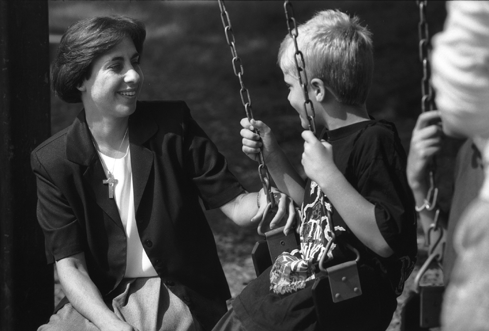 Holy Family of Nazareth Sr. Linda Yankoski talks to a child on a swingset at the Holy Family Institute in Pittsburgh in an undated photo. (Courtesy of Holy Family Institute)