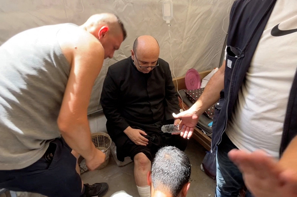 Parish priest of the Holy Family Parish, Fr. Gabriel Romanelli, receives medical attention, after he suffered light leg injuries following what initial reports said was an Israeli tank attack on the church, according to initial reports, at Al-Ahli Arab Hospital in Gaza City, in this still image taken from a video July 17, 2025. (OSV News/Reuters/Dawoud Abu Alkas)