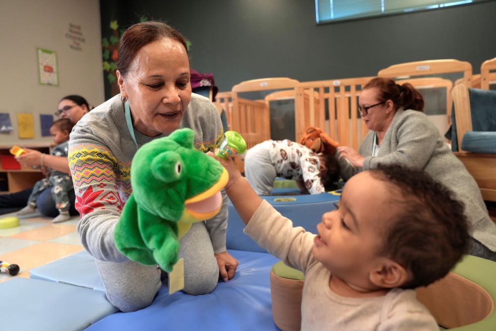 Volunteer Ydalina Luna Sosa uses a frog puppet for entertainment while supervising 10-month-old Leo Morgenweck. Volunteer Ydalina Luna Sosa uses a frog puppet for entertainment while supervising 10-month-old Leo Morgenweck.