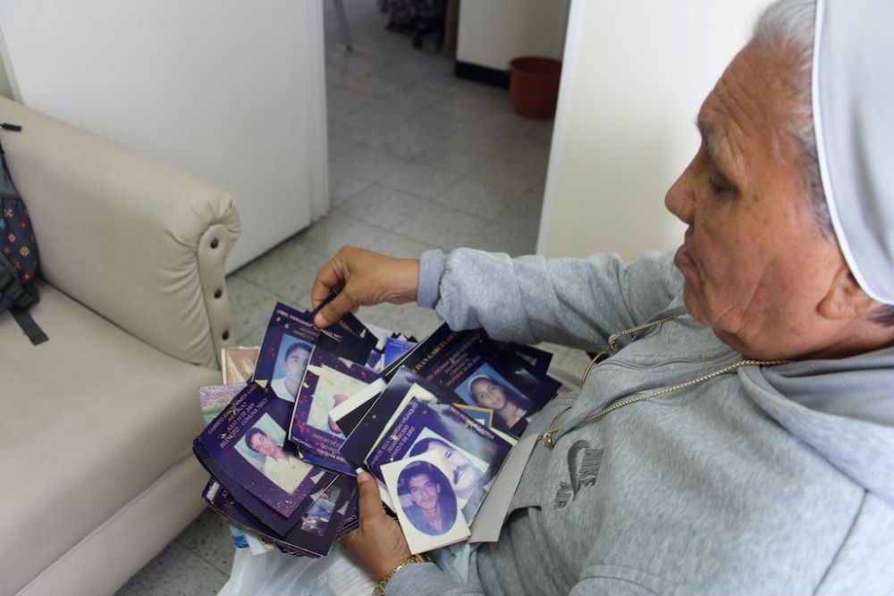 La Hna. Rosa Cadavid contempla fotos de víctimas de violencia en la Fundación Madre Laura Montoya. Voluntarios reorganizan la galería que durante años albergó imágenes de personas en duelo por la violencia en Medellín, Colombia. (Foto: Tracy L. Barnett)