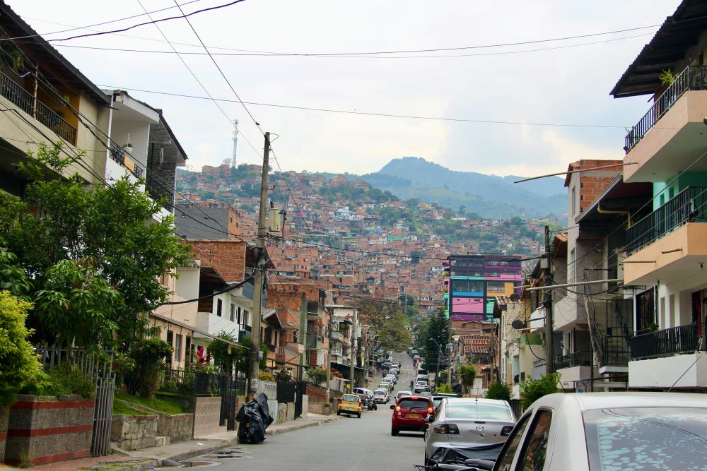 La Comuna 13 de Medellín, que en su día fue epicentro del conflicto armado colombiano, es ahora un símbolo de resiliencia y transformación. Desde esta tranquila calle residencial se extienden las densas colinas de la comuna, hogar de una comunidad que ha soportado la violencia, el desplazamiento y las operaciones militares, y que hoy vibra con arte, activismo y esperanza. (Foto: Tracy L. Barnett)