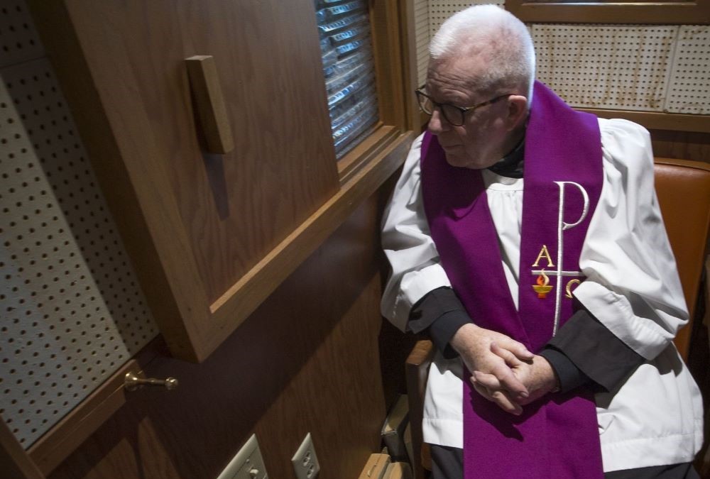 A priest hears confession.
