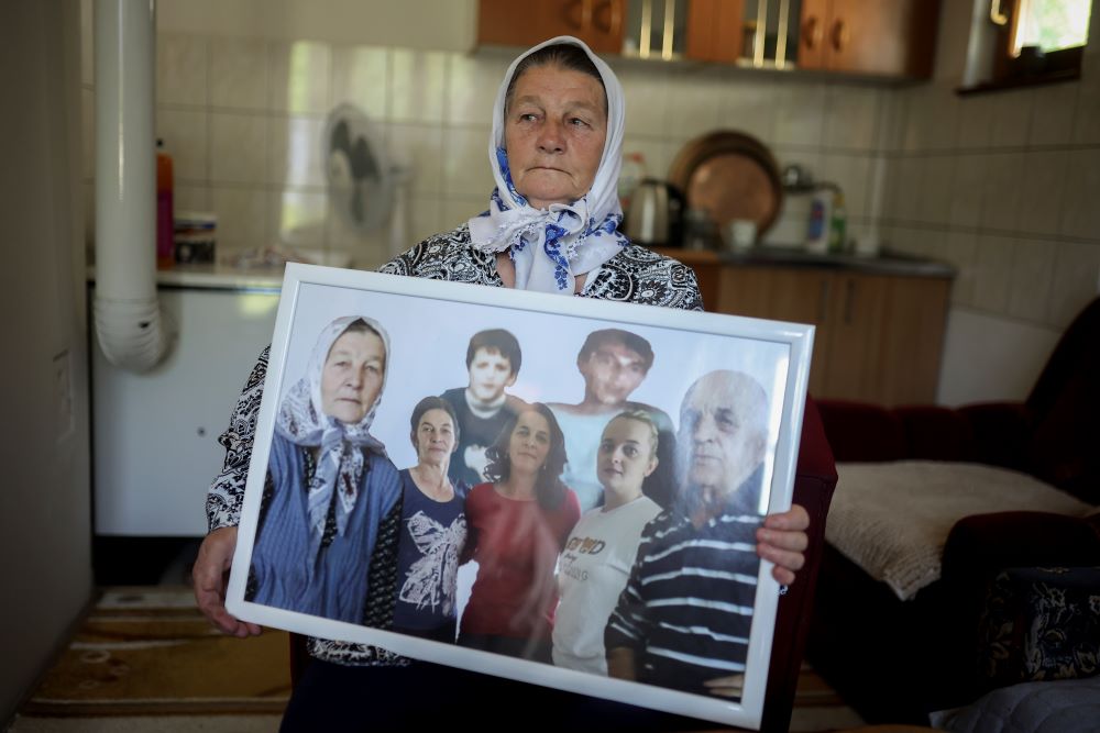 Sefika Mustafic poses for a photo while holding a picture of her family members, victims of the Srebrenica genocide. 
