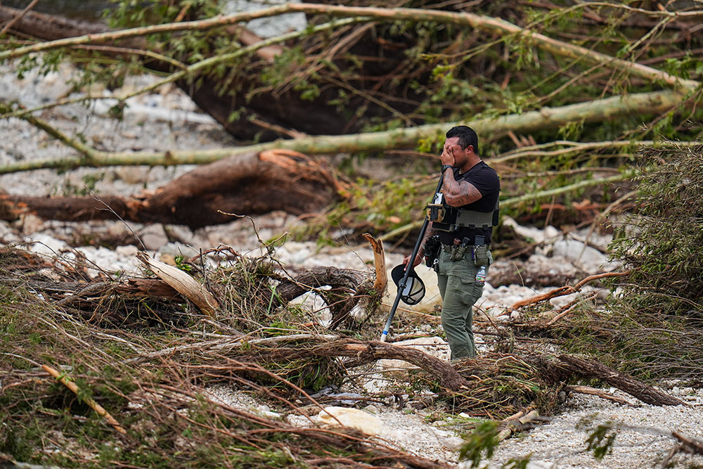 A sheriff's deputy pauses while combing through the banks of the Guadalupe River near Camp Mystic after a flash flood swept through the area Saturday, July 5, 2025, in Hunt, Texas. (AP/Julio Cortez)