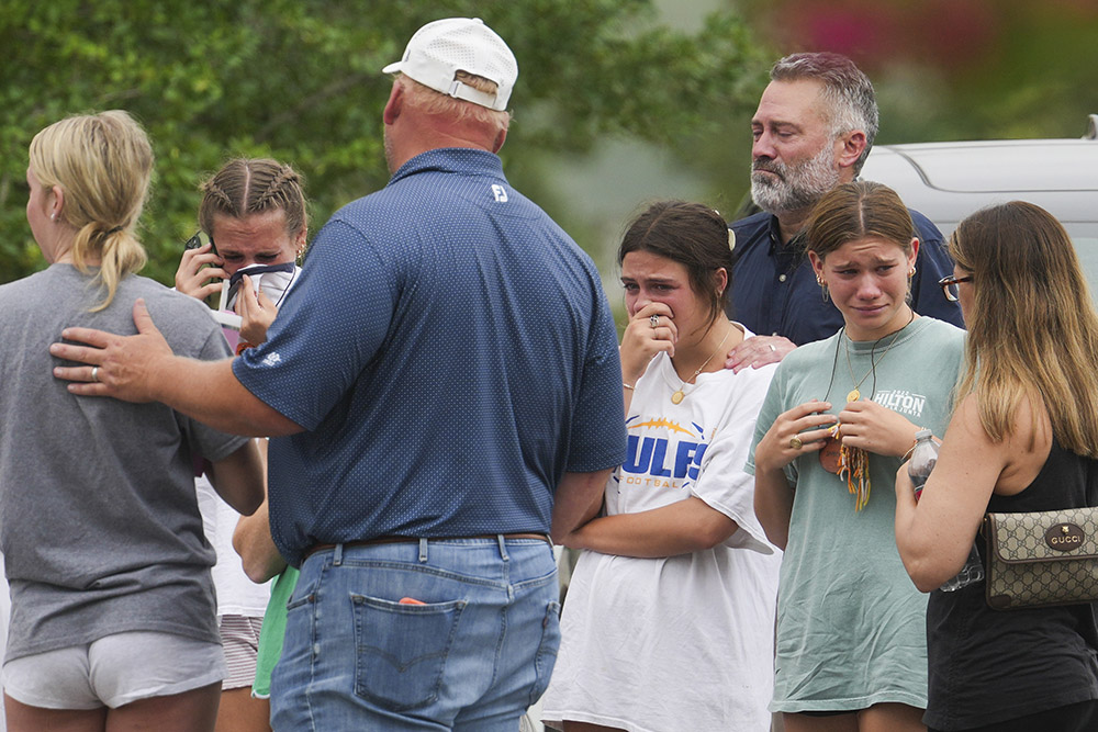 People comfort each other outside the Butt-Holdsworth Memorial Library in Kerville after heavy rainfall caused the Guadalupe River to flood and damage several communities in Central Texas, Saturday, July 5, 2025. (Houston Chronicle via AP/Jason Fochtman)