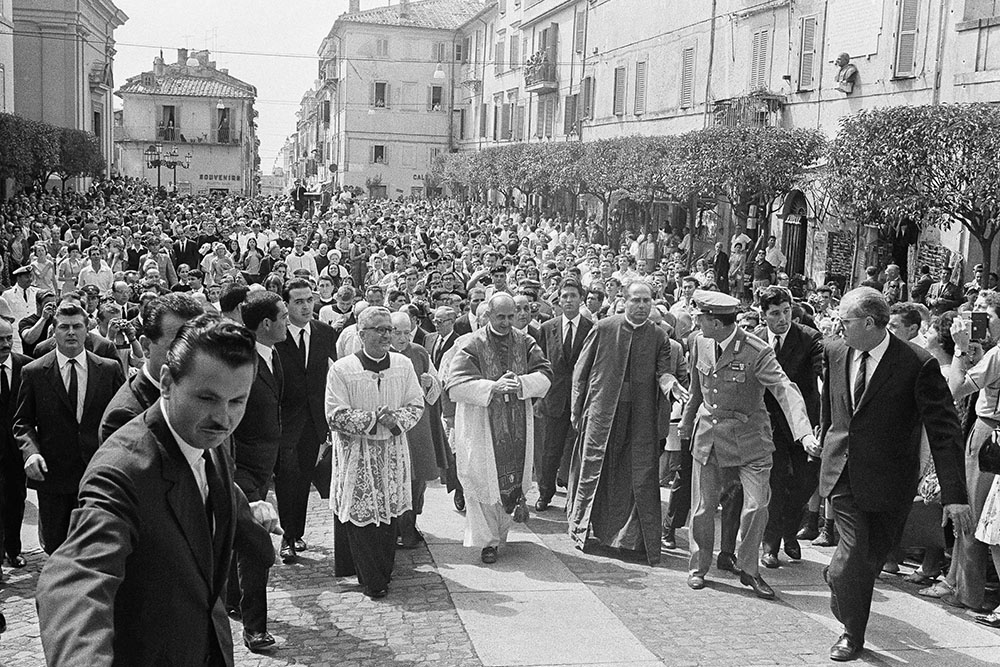 Pope Paul VI, center, is followed by a crowd as he walks the short distance from the local parish church, St. Thomas of Villanova, to the papal summer residence in Castel Gandolfo, Italy, Aug. 15, 1965. The pontiff celebrated the Assumption Day Mass in the little church. (AP/Giulio Broglio)