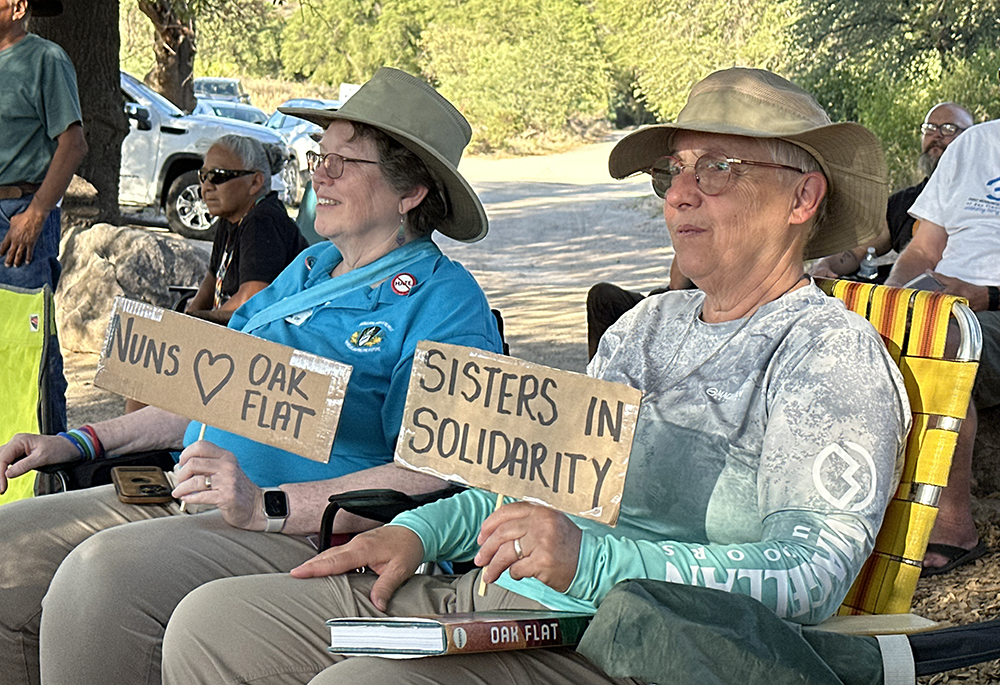 Dominican Sr. Susan Leslie, left, and Sr. Barbara Battista, of the Sisters of Providence, hold supportive handmade signs and listen to speakers at the Oak Flat event. (Courtesy of Land Justice Futures)
