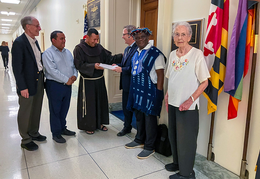 Franciscan Fr. Juan de la Cruz Turcios, parochial vicar of St. Camillus Parish in Silver Spring, Maryland, is joined by parishioners as he hands letters seeking protection for immigrants to Jeremy Hekhuis, chief of staff to Rep. Jamie Raskin, D-Md., June 26, 2025. (NCR photo/Patricia Zapor)