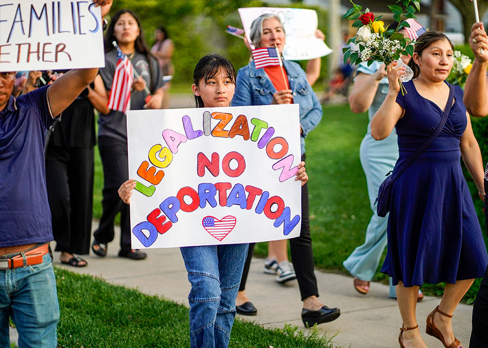 La gente asiste a una marcha y manifestación a favor de los inmigrantes tras una misa en español en la iglesia de San Juan Evangelista en Riverhead, Nueva York, Estados Unidos, el 22 de junio de 2025, festividad del Cuerpo y la Sangre de Cristo. El ministerio social de la parroquia de San Juan organizó el evento, que atrajo a unos 300 participantes. La parroquia atiende a un gran número de inmigrantes latinoamericanos que viven y trabajan en el extremo este de Long Island. (Foto: OSV News/Gregory A. Shemitz