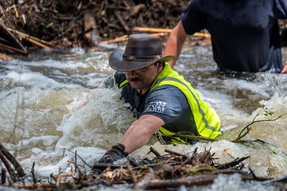 Man stands in the Guadalupe River as he tries to clear debris in Center Point, Texas.