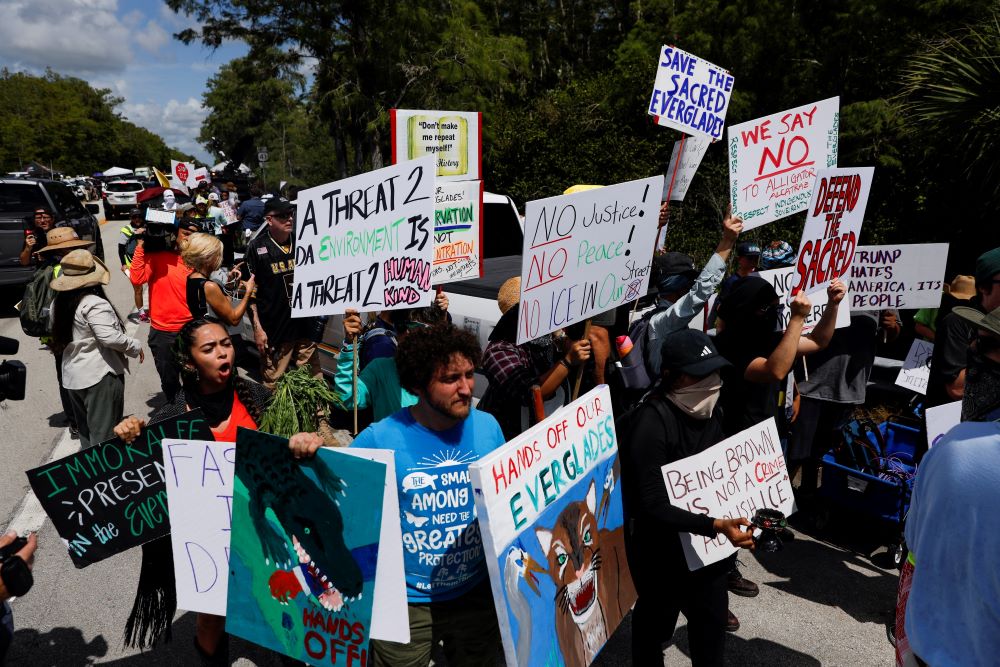 Protesters flank an entrance road at a temporary migrant detention center nicknamed "Alligator Alcatraz." 