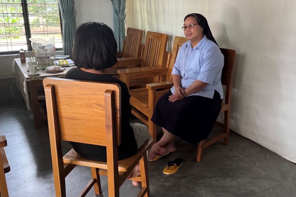 A nun faces a girl, both sitting in chairs, during counseling session.