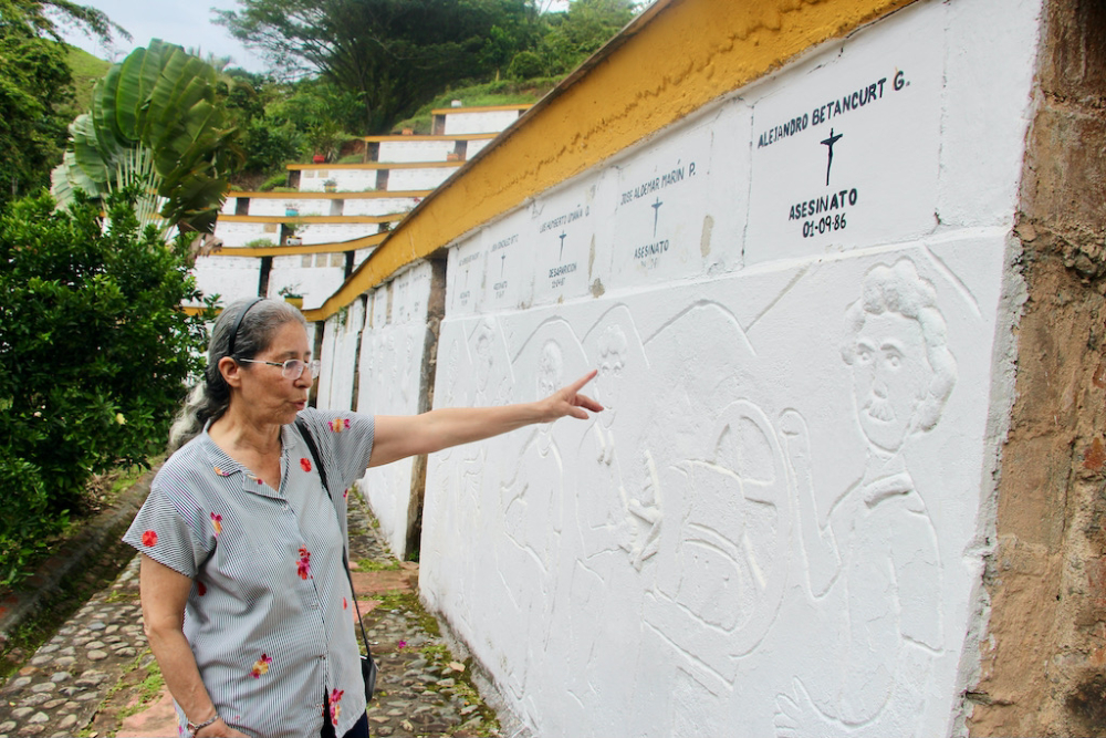 La Hna. Teresita Cano señala el bajorrelieve de Alejandro Betancur, uno de los 235 que bordean las paredes del osario, que mira hacia Trujillo desde el Parque Monumento a la Memoria. (Foto: Tracy L. Barnett)
