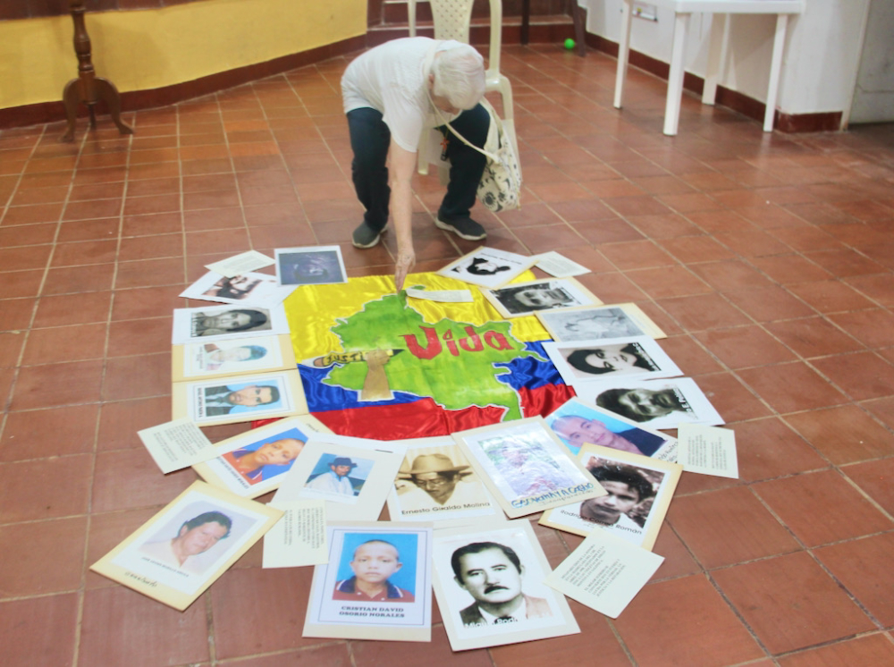 La Hna. Maritze Trigos levantó un altar en memoria de las numerosas víctimas de Trujillo: una bandera de Colombia convertida en pancarta, sobre la que se dibujó la silueta del mapa del país con el estampado de las palabras "Justicia" y "Vida"; y alrededor se dispuso las fotografías. (Foto: Tracy L. Barnett)