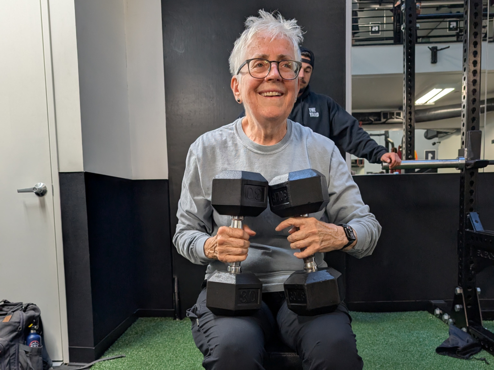 Sr. Pat Farrell holding two 30-pound dumbbells while training with trainer and spotter Jake Levine at The Yard gym. (Erin Edwards)
