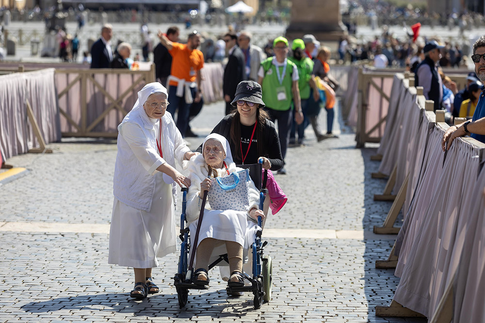 A religious sister and a volunteer help a sister in a wheelchair get to her place in St. Peter's Square at the Vatican for a session of prayer and catechesis during the Jubilee of People with Disabilities April 29, 2025. (CNS/Pablo Esparza)