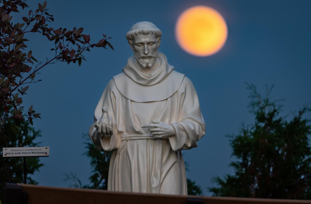 A hunter's moon rises behind a statue of St. Francis of Assisi on the grounds of the National Shrine of Our Lady of Champion in Champion, Wis., Oct 8, 2022 (OSV News/CNS/Sam Lucero)