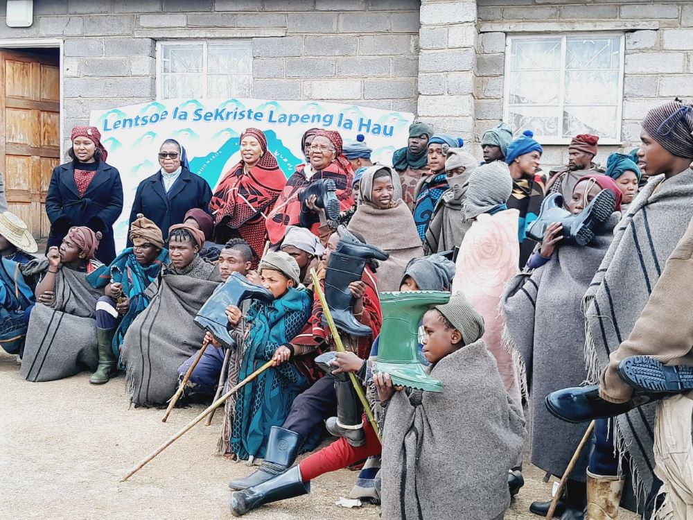 Shepherd boys and villagers gather with sisters outside a stone building where Sr. Vitalina Mohale runs a school and farming project. 