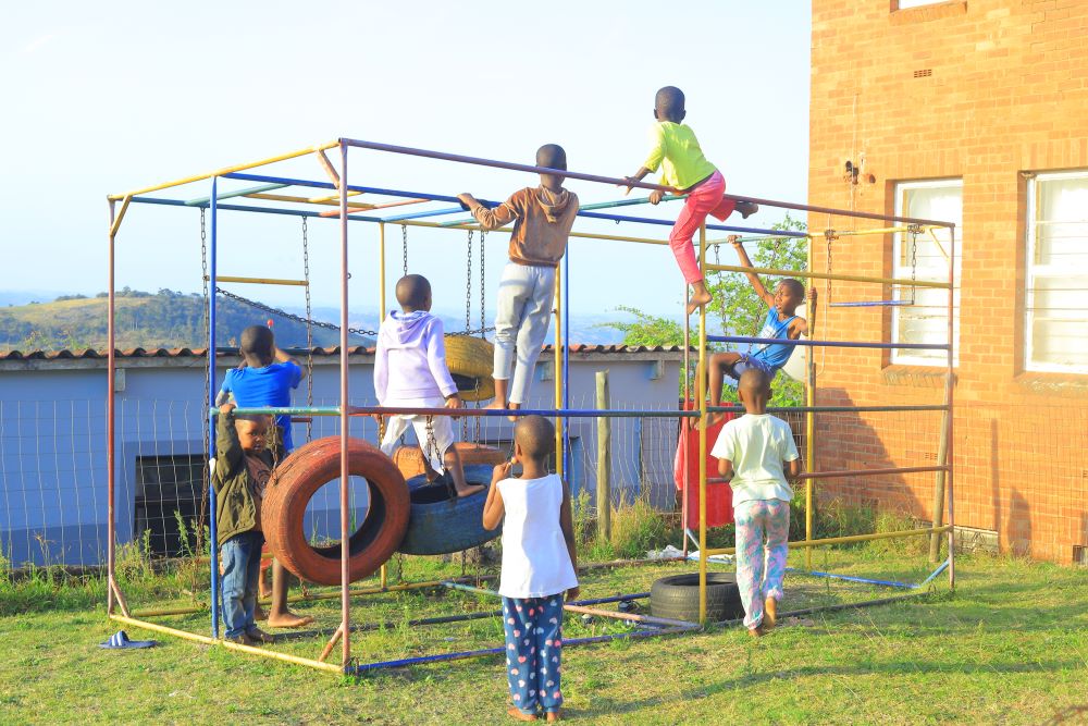 Children play on a worn jungle gym at an outreach center in Durban, South Africa.