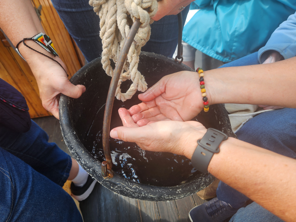 A ritual of connection as participants in the Pilgrimage of Hope for Creation placed their hands in the river water, silently offering a prayer of gratitude or lament. (GSR photo/Chris Herlinger)