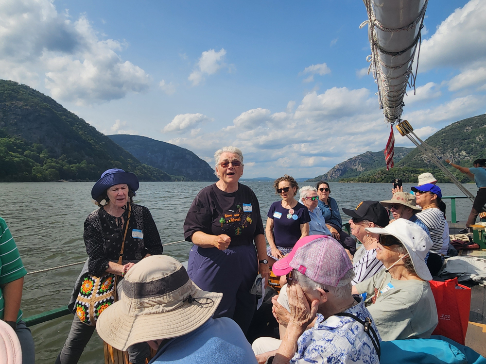 Dorothy Calvani, a lay member of ROAR, leads participants in song in front of a view of the Hudson River looking north. (GSR photo/Chris Herlinger)