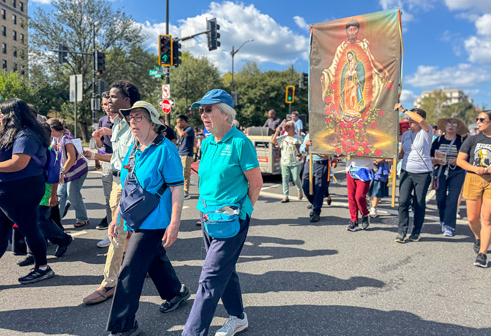 Holy Cross Srs. Ruth Nickerson, right, and Brenda Cousins, walk down a main street in Washington Sept. 28, 2025 during a procession of about 1,000 to mark the World Day of Migrants and Refugees. The women religious say they participated to show support and because of concerns about how migrants have been treated during the Trump administration's immigration crackdown this year. (GSR photo/Rhina Guidos)