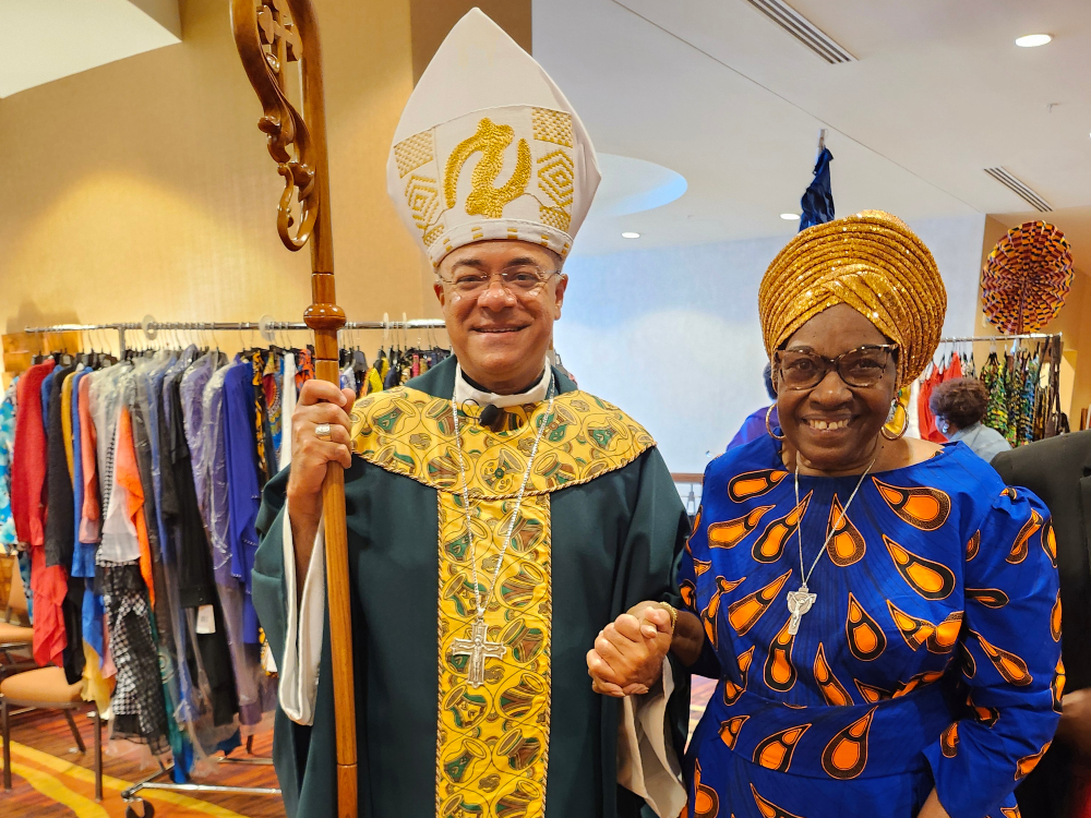 Sr. Jannette Pruitt, dressed in a blue dress with large orange drop-shaped spots and a gold colored headwrap, and Archbishop Shelton Fabre of Louisville, Kentucky dressed in a green and yellow vestments with a white, gold-embroidered mitre.