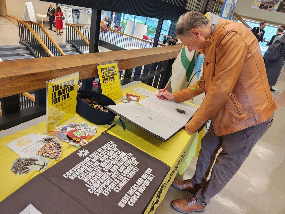A man writes in a book at a conference display.