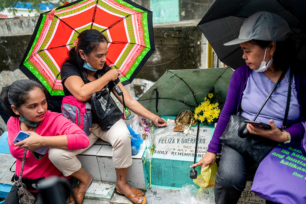 A woman lights a candle on the grave of her mother at the Manila North Cemetery during All Saints' Day in Manila, Philippines, Nov. 1, 2022. (CNS/Reuters/Lisa Marie David)