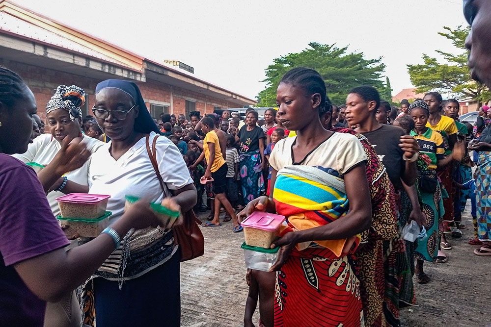 Sr. Mary Ojonugwa Unwuchola distributes cooked rice to survivors of violence at the International Market Camp in Makurdi, Benue State, Nigeria. (John Chukwu)